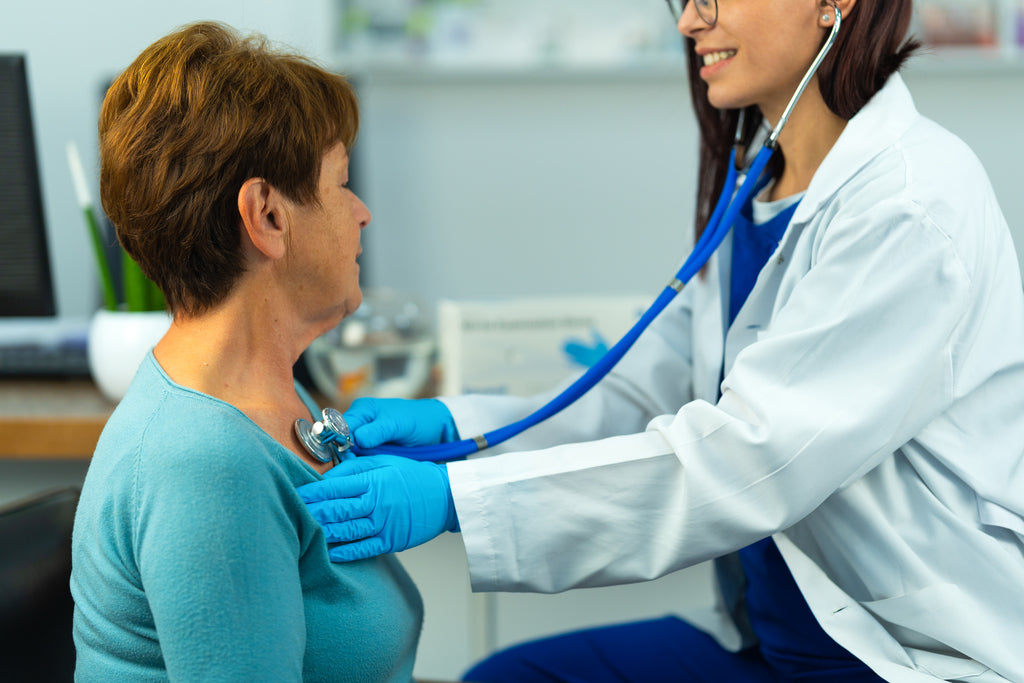 Doctor listens to a patient’s chest with a stethoscope while wearing blue Raxwell gloves. Photo demonstrates medical exam dexterity.